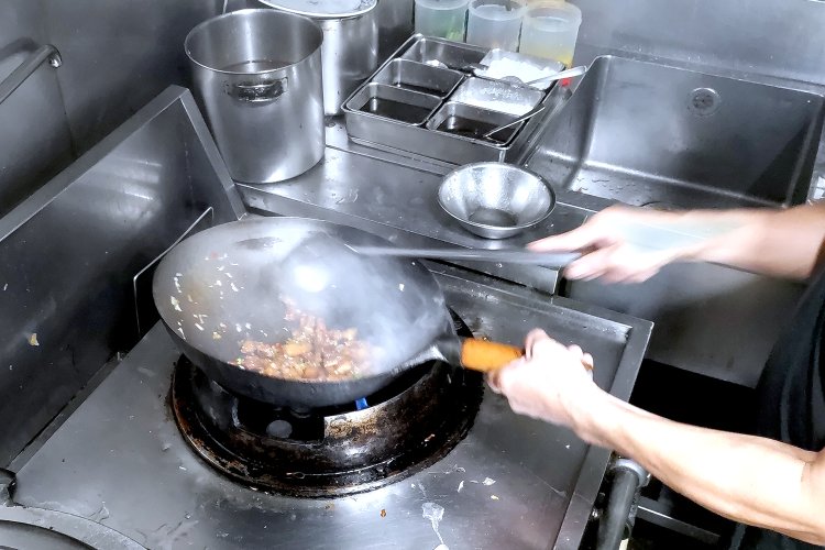 食材を加熱しながら紹興酒を加え、一気に炒めていく。紹興酒は、香り付けのために使用。