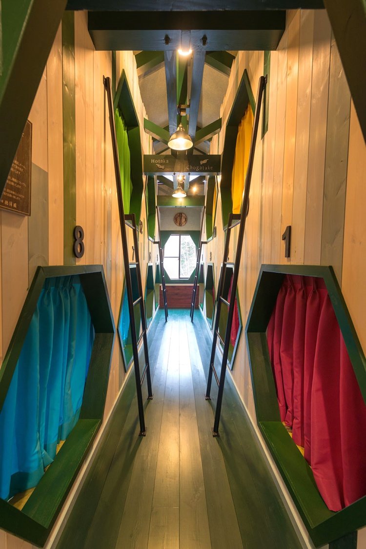 ハチの巣をモチーフにした六角形の入口とカラフルなカーテンが楽しい相部屋「カラマツ」。