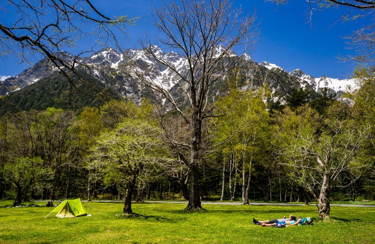 明神岳・前穂高岳を望む徳沢キャンプ場（写真＝上高地観光旅館組合）。