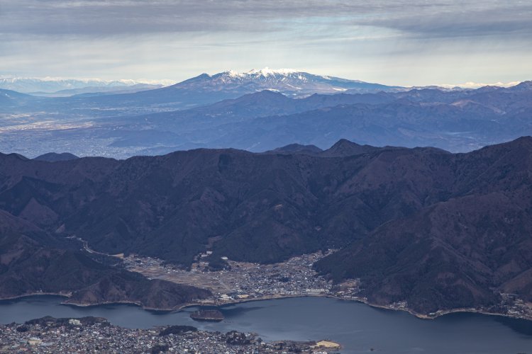 富士山と逆方向を向くと、手前に河口湖、その向こうに八ヶ岳が見えた。左奥にはうっすらと北アルプスも。