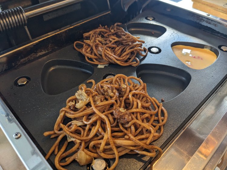 焼きおにぎりメーカーに紅生姜を置き、卵液を流し入れ、その上に仕込んでおいた焼きそばをのせる。