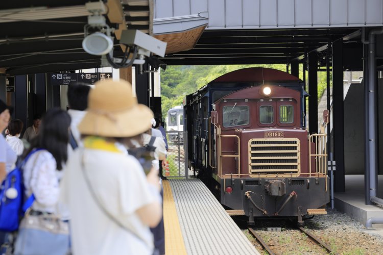立野駅に入線する「ゆうすげ号」に乗客の誰もが注目。