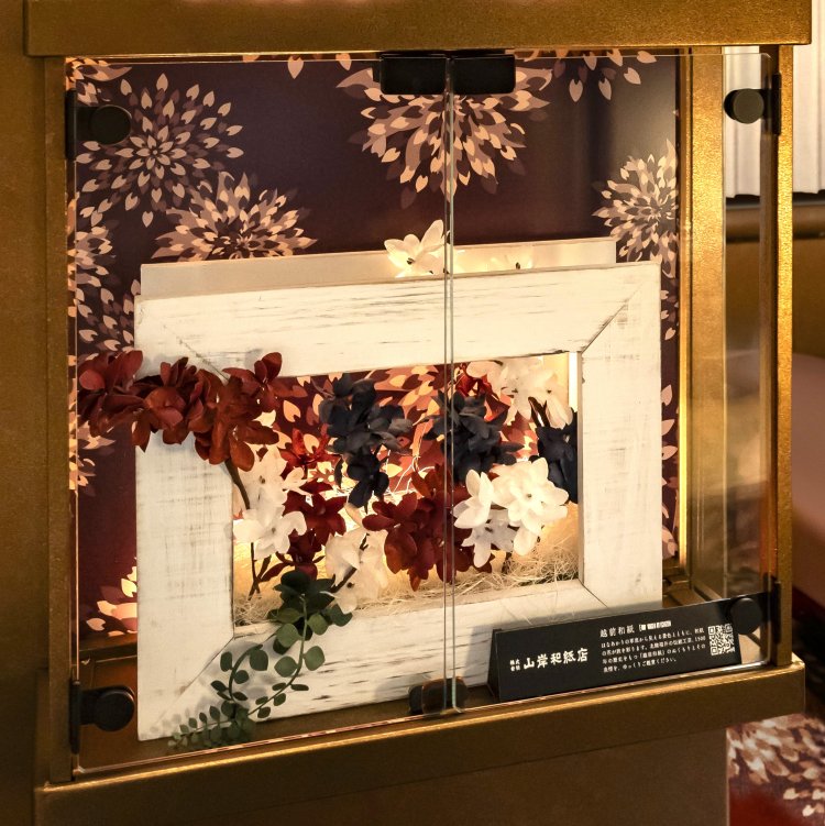 「スーペリアグリーン車」を彩る出雲たたら製鉄一輪挿し（上）と、運転区間に合わせた調度品の越前和紙フラワーアート。