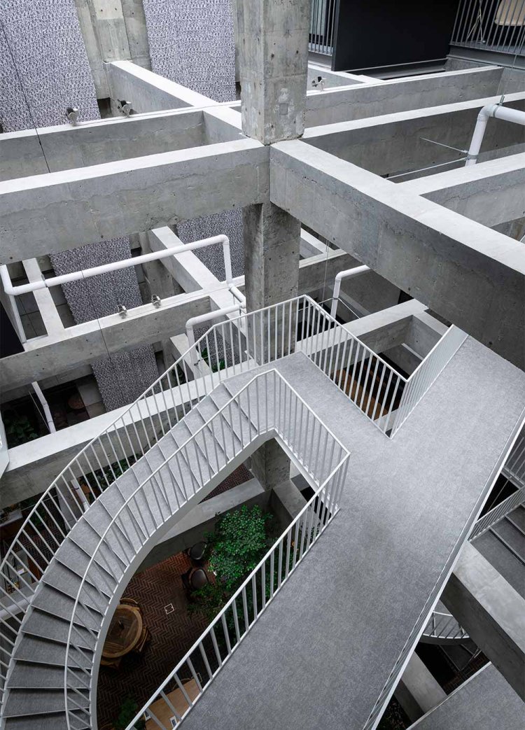 4階までコンクリートむき出しの吹き抜け。見下ろすとまるでエッシャーの絵だ。張り巡らされたパイプも作品で、中のLEDが光る。