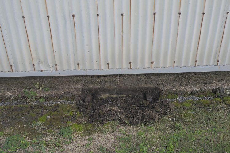 反対側の駐車場側の壁面を職員が掘り起こしてみると、600mm軌間のレールが見つかった（2024年10月撮影）。