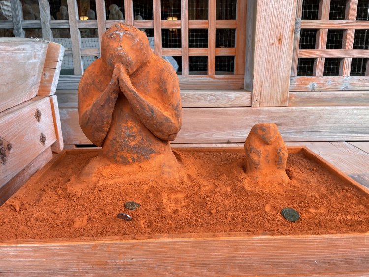 合掌する猿の像に朱色の粉が塗られている。