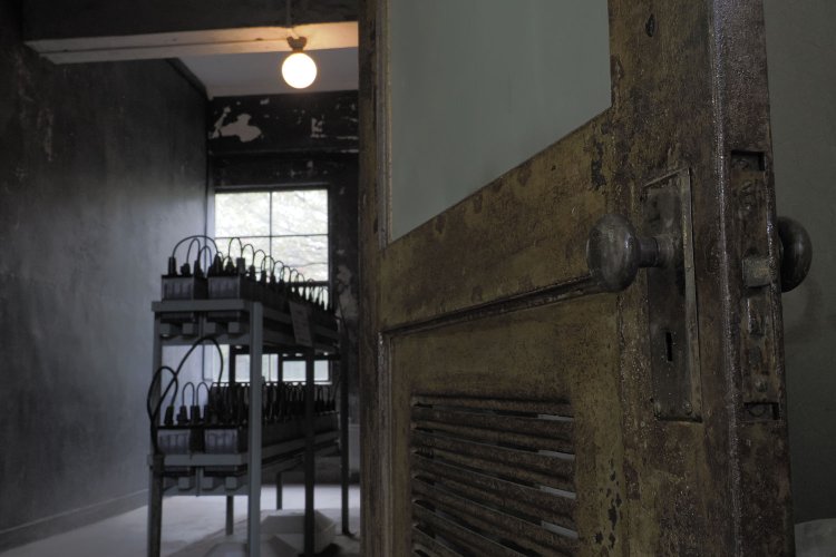 1階の蓄電池室。ドアや照明器具は戦前のもの。蓄電池室の壁面も機銃掃射によってすり鉢状の弾痕があった。