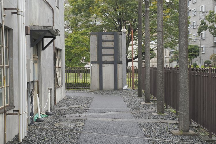 北側には変電設備の痕跡が残る。等間隔に並ぶ電柱は受電施設の名残りで、奥には防護壁が一部保存されている。