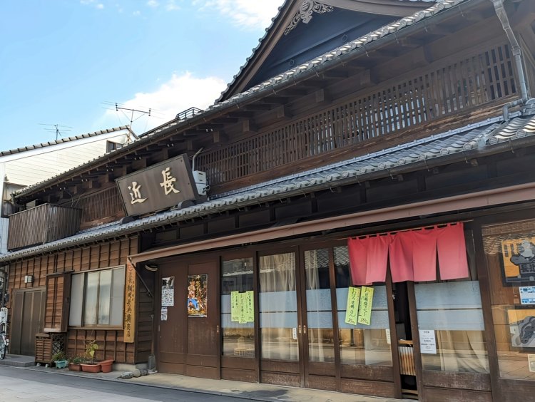 歴史を感じさせる立派な店構え。赤い暖簾が街の景色のいい差し色になっている。