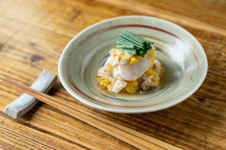 『酒井商会』の炙りとらふぐと菊花のおろし和え。ふぐの淡いながら芯のある味わいを、菊花の⾹りと⾃家製ポン酢の爽やかな⾵味が引き⽴てる。⽇本酒が進む⼀⽫（撮影＝海⽼原俊之）。