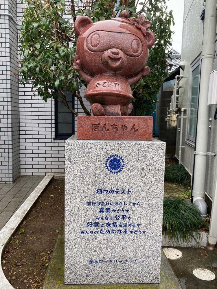 館林市観光キャラクター・ぽんちゃん像。タヌキ色に合わせて赤御影石が使われている（東武鉄道館林駅前）。