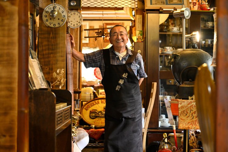 叔母が刺繍したエプロンを着ける井上さん。「頼んでないけど」と言いつつ満面笑顔。