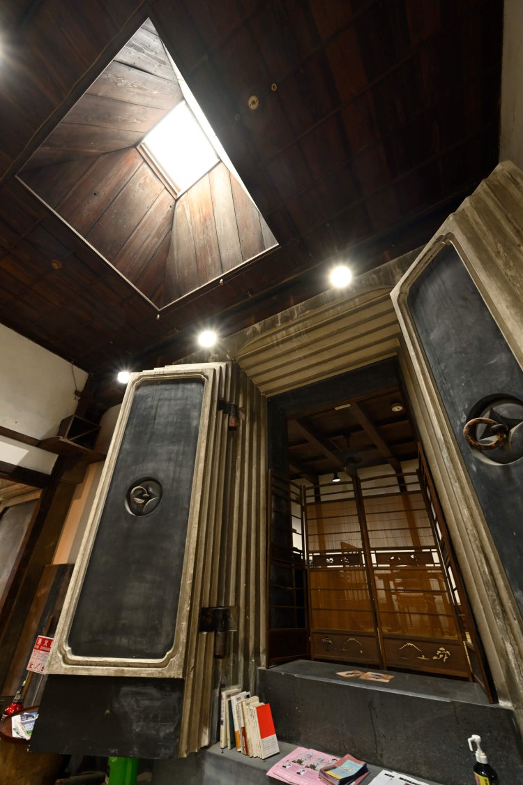 吹き抜けの窓から光が差し込む通路に面し、重厚な蔵の扉が開く。