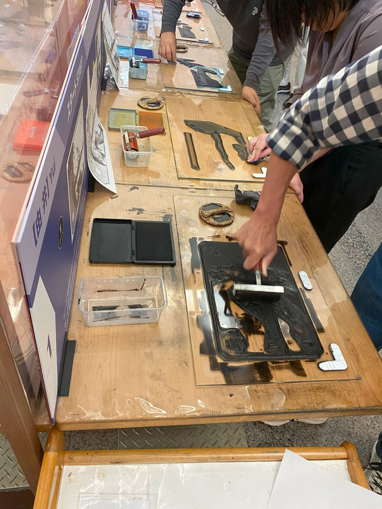 ローラーにインクを付け、版の凸部分にインクをのせていく。版画摺り体験は330円（1セット用紙2枚）。