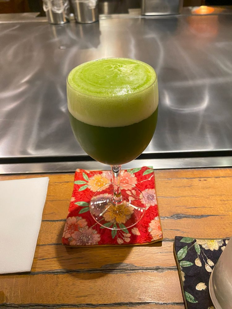 ウェルカムドリンクの抹茶ビール。見た目は抹茶のような泡だが、鼻を近づけるとビールの香り。甘みと渋味のバランスが心地いい。ウェルカムドリンクはノンアルコール（静岡茶ソーダ）も選べる。
