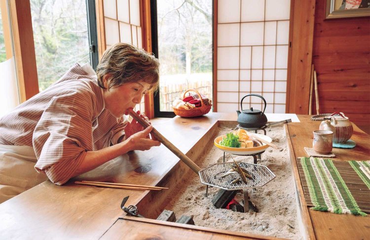 火吹き棒で炭火の火力を調整し、琵琶湖のモロコを焼く喜美枝さん。