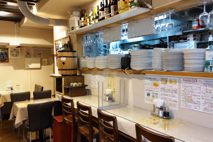 客席は2～4人掛けのテーブル席が中心。カウンター席の向こう側は厨房になっている。