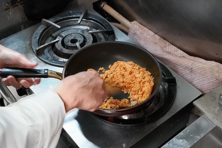 ご飯にケチャップを加えて炒めていく。具材はベーコン、タマネギ、マッシュルーム。