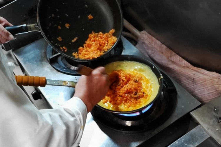 別のフライパンで卵を加熱し、その上にケチャップライスを投入する。