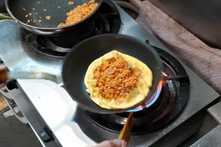 ケチャップライスの外周を卵で包みながら、形を丸く整えていく。