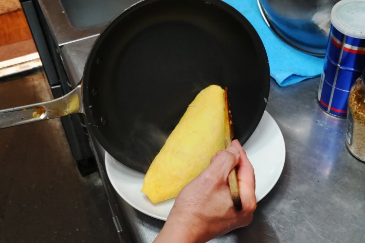 オムライスが崩れないよう、慎重にお皿へ盛り付ける。あとはソースをかけるだけ。