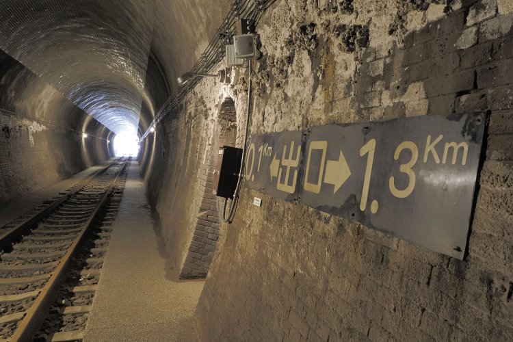 壁面の距離標が「0.1km」を示すころ、前方の明かりも大きくなってきた。レールはまた普通のバラスト敷きへと戻っている。