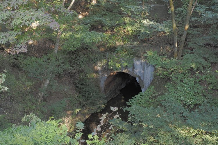 大日影トンネルを出た先の遊歩道橋梁から眼下をのぞくと、深沢川は河川隧道（ずいどう）となっている。トンネル建設と同時に河川隧道も整備され、こちらはいまも現役である。