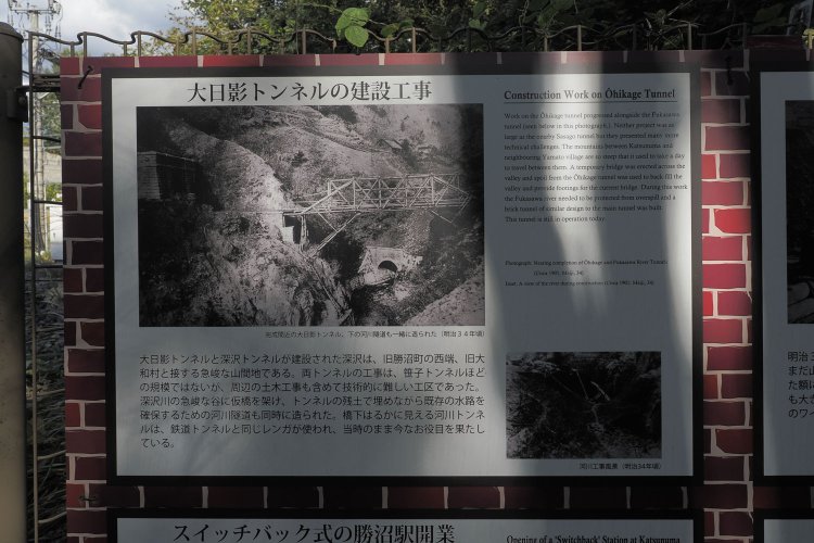 大日影トンネル周辺の工事状況を知らせる案内板。この案内板は勝沼ぶどう郷駅側に掲示されている。古写真には建設時の状況が写っており、深い谷間に造られたのが分かる。
