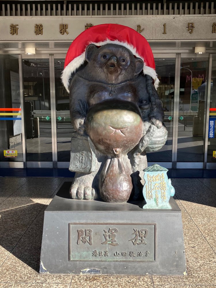 有名な新橋駅前ビルの「狸広」像。笠の部分をすっぽり覆う、巨大サンタ帽がかぶせられている。