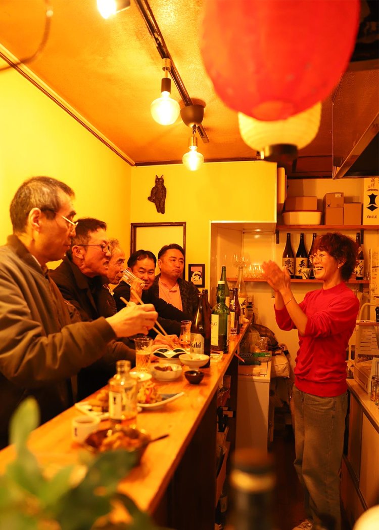 6、7人で満員の『青木商店』。「飲むね～」（店主）、「飲ますね～」（客）と、狭さが楽しい一体感を生む。「女性店主の立ち飲みも増えてきました」と店主・奈緒子さん。