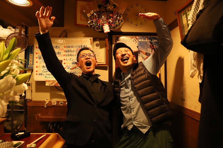 左から、常連の大さん、ライター・鈴木。「三角でつながった縁にマルッ！」。