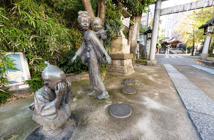 池尻稲荷神社の裏門に立つ、かごめかごめ中の銅像。