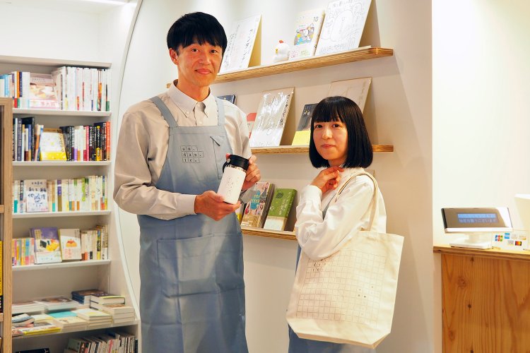 オリジナルのトートバッグやタンブラーも販売。左が店長の前田さん。
