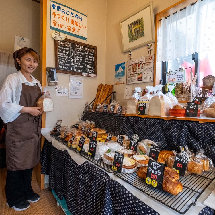小麦本来の甘みを味わえる匠食パン450円を手にする店員の松尾志江さん。毎日約50種のパンが並ぶ。