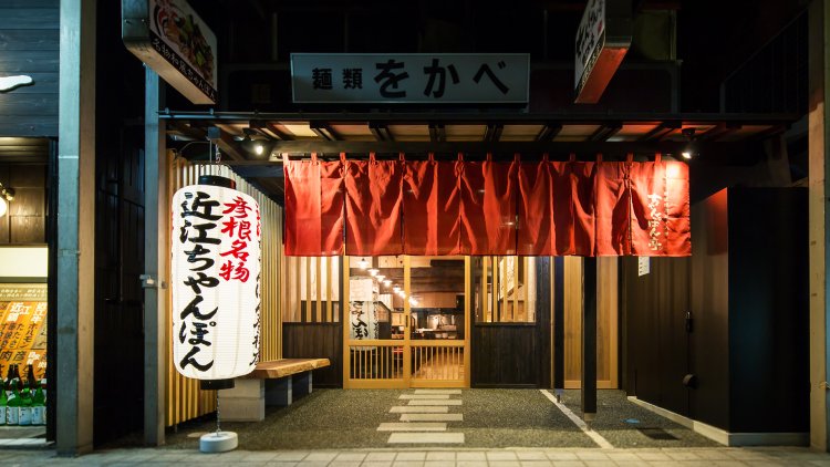 『麺類をかべ』の当時の看板がいまも掲げられる彦根駅前店。