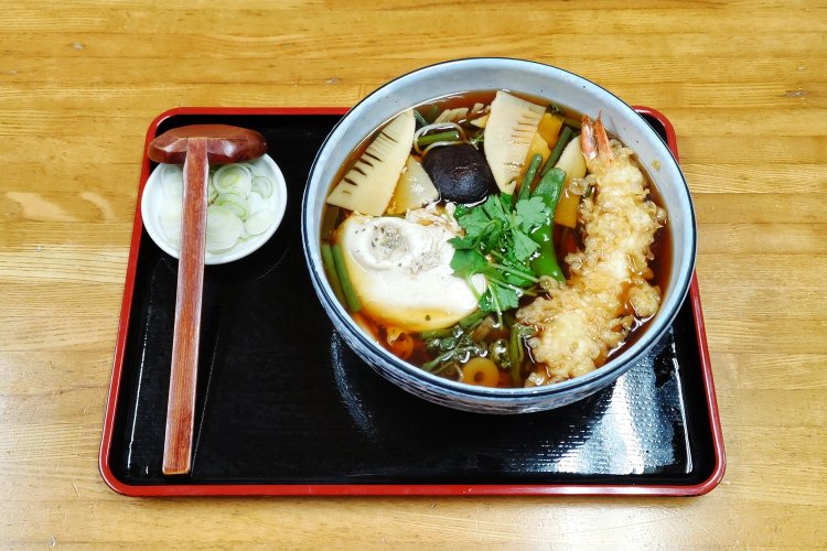 山菜やエビ天、煮卵などの具材を惜しみなく盛り付けた地獄そば。唐辛子をかけたら地獄っぽいかも。