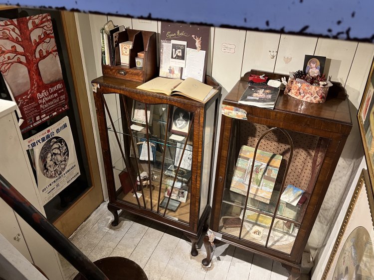 地下1階のギャラリー。額に入れられた絵画や本、人形の衣装など、さまざまな創作物が展示されている。