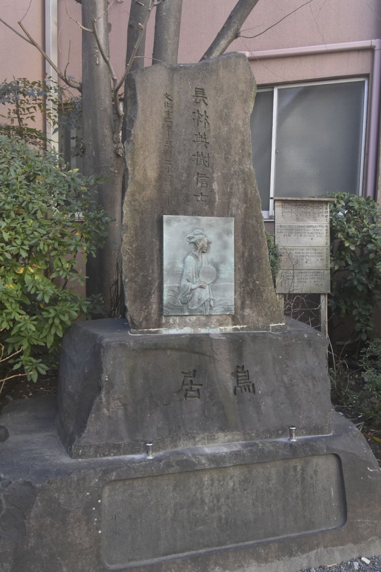 鳥居清長の碑。遠目でも顔が光って見える。