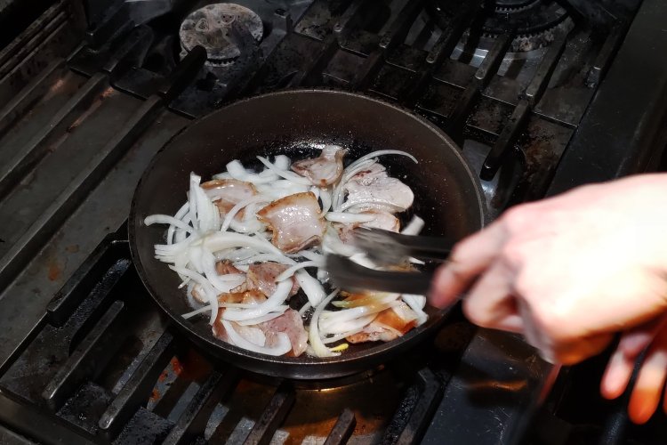 豚肉の両面が焼けてきたら、タマネギをたっぷり加え、トングで混ぜながら炒めていく。