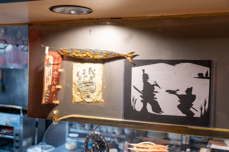 常連客から贈られた「目黒のさんま」の切り絵とさんまの実物大マグネット。
