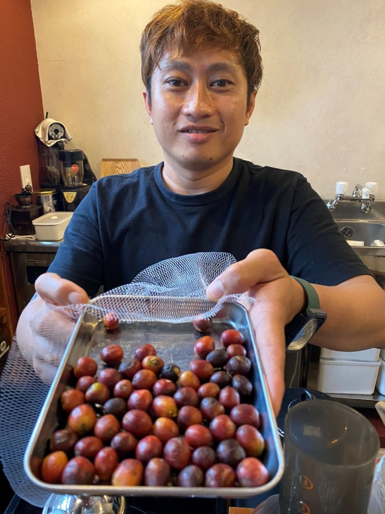 ジョークも弾む店主のリノ・センレワさんと、ジャワ島の農園で摘んできたコーヒーの実。