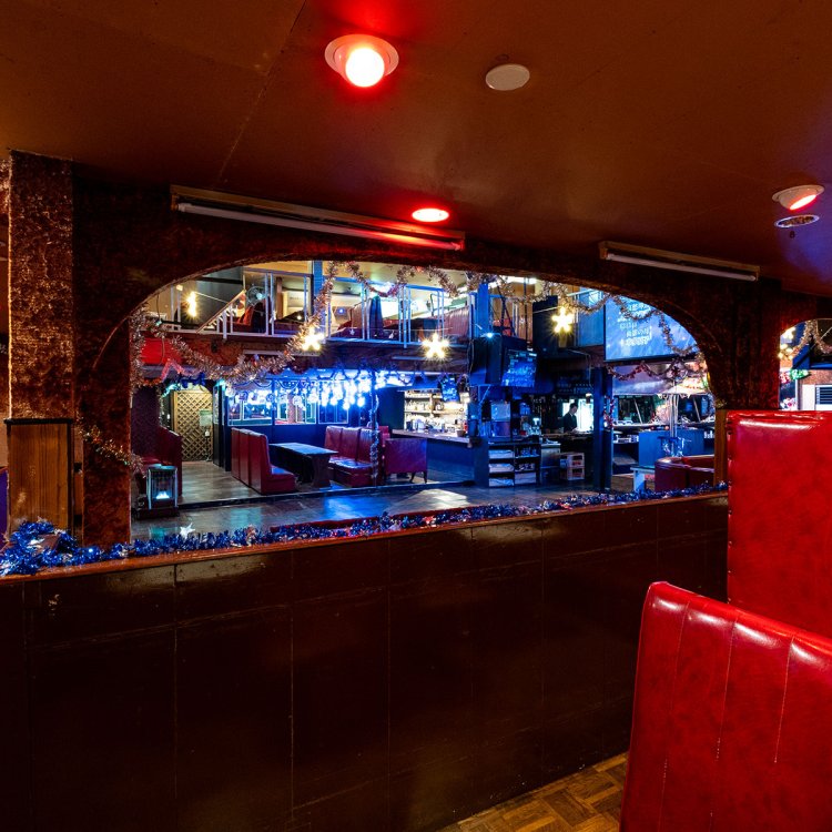 フロアを囲むように座席が配された吹き抜けの店内。赤くて高い座席の背もたれなど随所に時代の息吹を感じる。