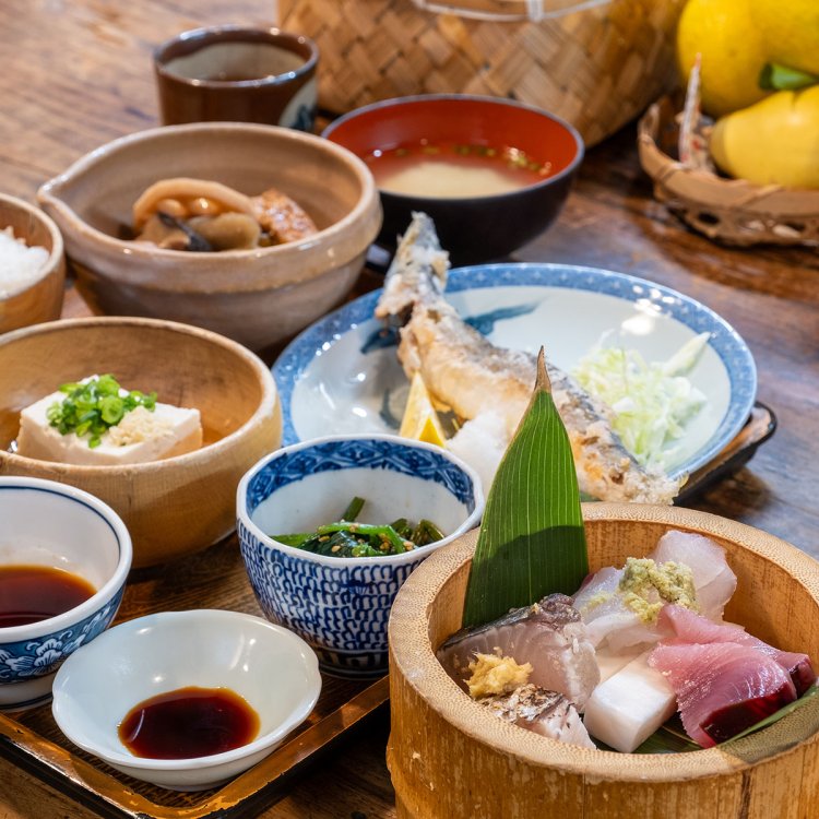 揚げた魚にお煮しめや小鉢が並ぶ田吾作定食とちょっと刺身2000円はランチタイム限定メニューで、コーヒーも付く。