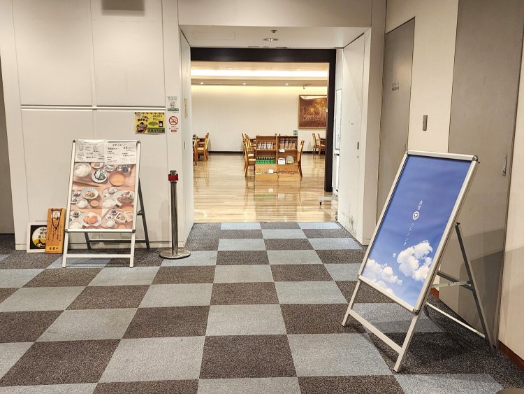 南館のエレベーターで14階へ。入り口には空色の立て看板。