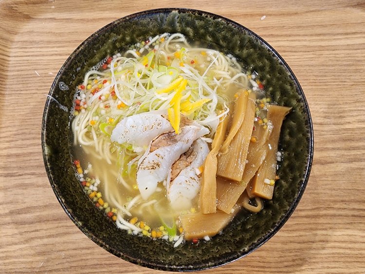 魚の切り身がのったあら出汁ラーメン。具はほかにネギ、ユズ、メンマ、アラレ。