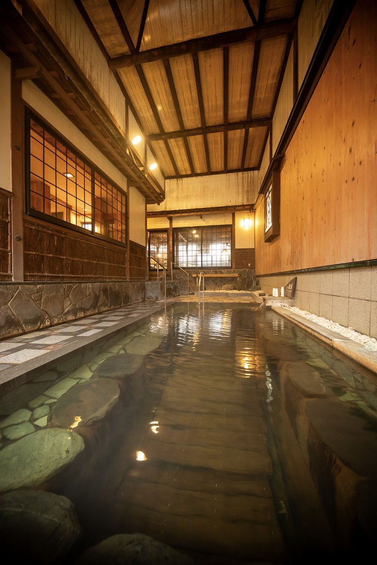 岩井温泉の老舗宿『岩井屋』。立つと胸まで浸かる深い浴槽と開放感ある高い天井が特徴だ（撮影＝中野一行）。