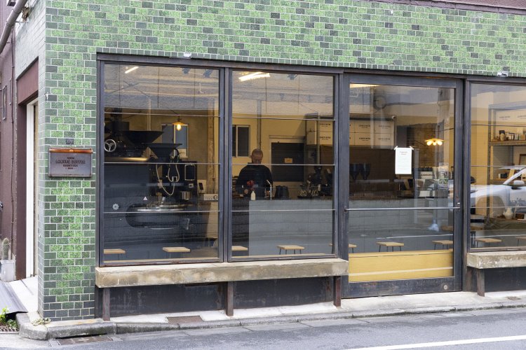 外壁の緑色のタイルは近隣でも見かける昔ながらのもの。店奥の棚には整然と焙煎豆や器具が並ぶ。