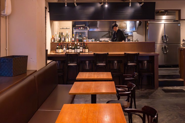 ゆったり間隔が空いたテーブル席。奥にはオープンキッチン。ランチ営業もあり。