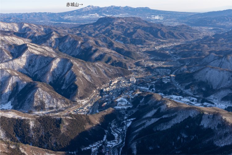 谷川岳すぐ麓には水上の町が見える。奥に三峰山、さらに奥には赤城山が見える。