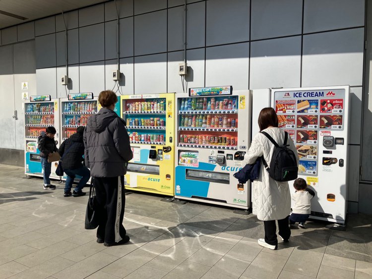 Suicaのペンギン像の向かいにはズラリと自動販売機が並び、人々が次々と利用していた。